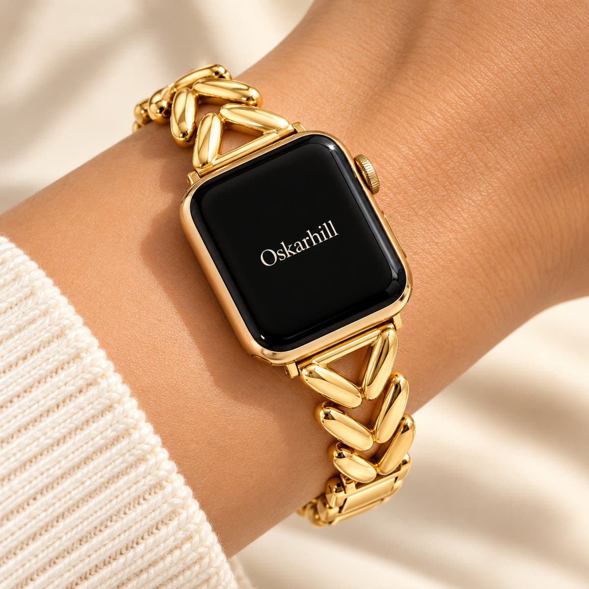Monelle gold chevron-link Apple Watch band worn with an ivory knit sleeve
