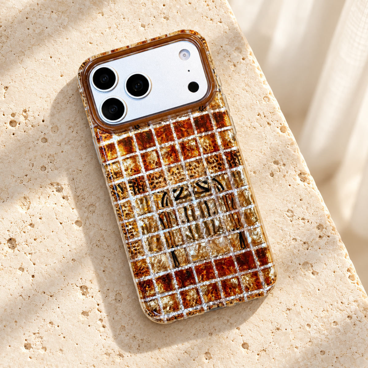Plaid Amber Shimmer iPhone case in an overhead flat-lay on cream stone.