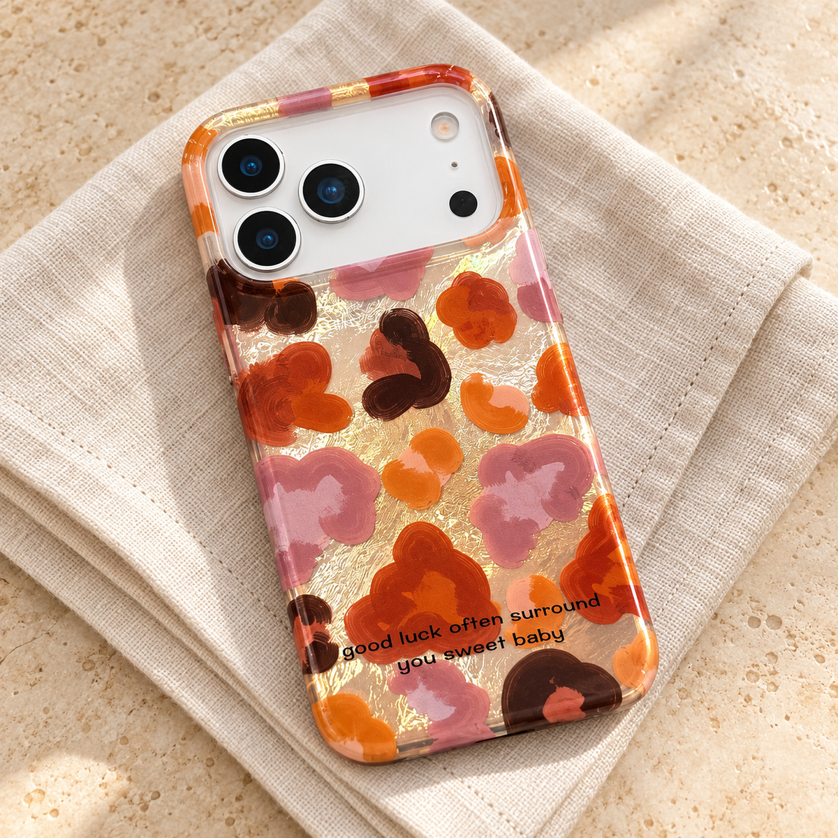 Autumn Mix case resting on ivory linen, with its glossy floral back and white phone camera area visible.