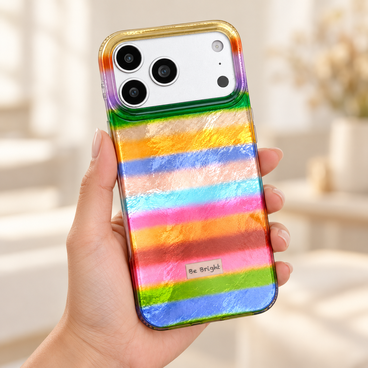 Be Bright rainbow stripe iPhone case — handheld rear view.