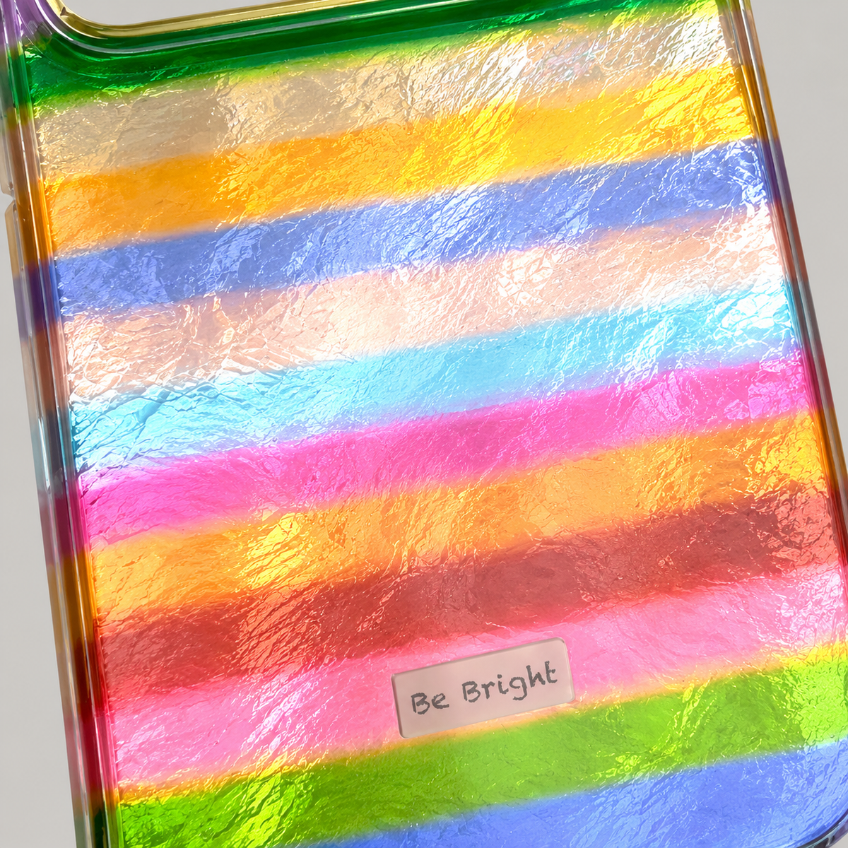 Be Bright rainbow stripe iPhone case — reflective rainbow texture close-up.