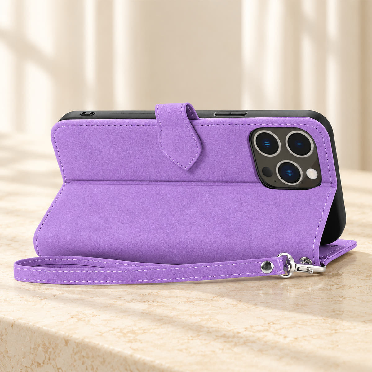 Botanical wallet iPhone case in Lavender folded into a landscape stand, rear view showing the plain back, camera opening and matching wrist loop.