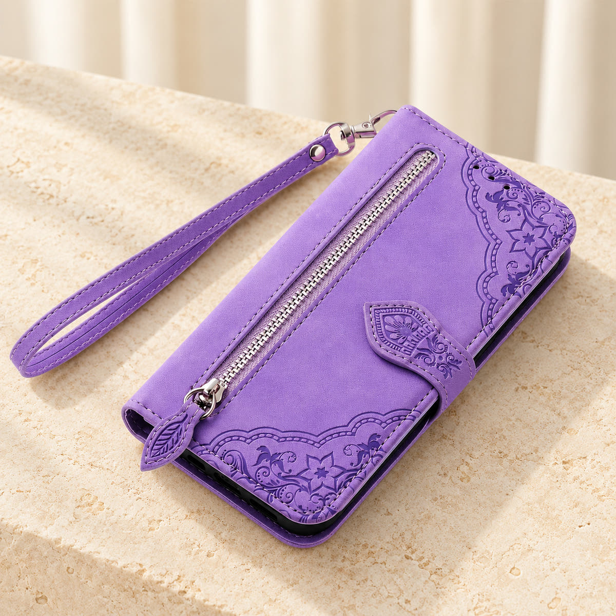 Botanical embossed wallet phone case in Lavender, tabletop view of the closed folio with external zip pocket and matching wrist strap.