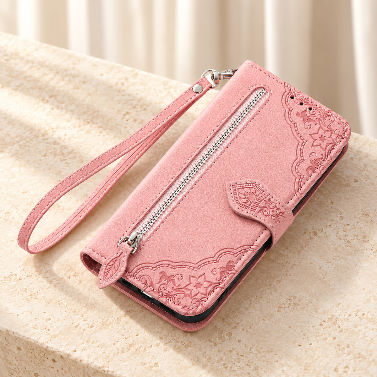 Botanical embossed wallet phone case in Pink, tabletop view of the closed folio with external zip pocket and matching wrist strap.