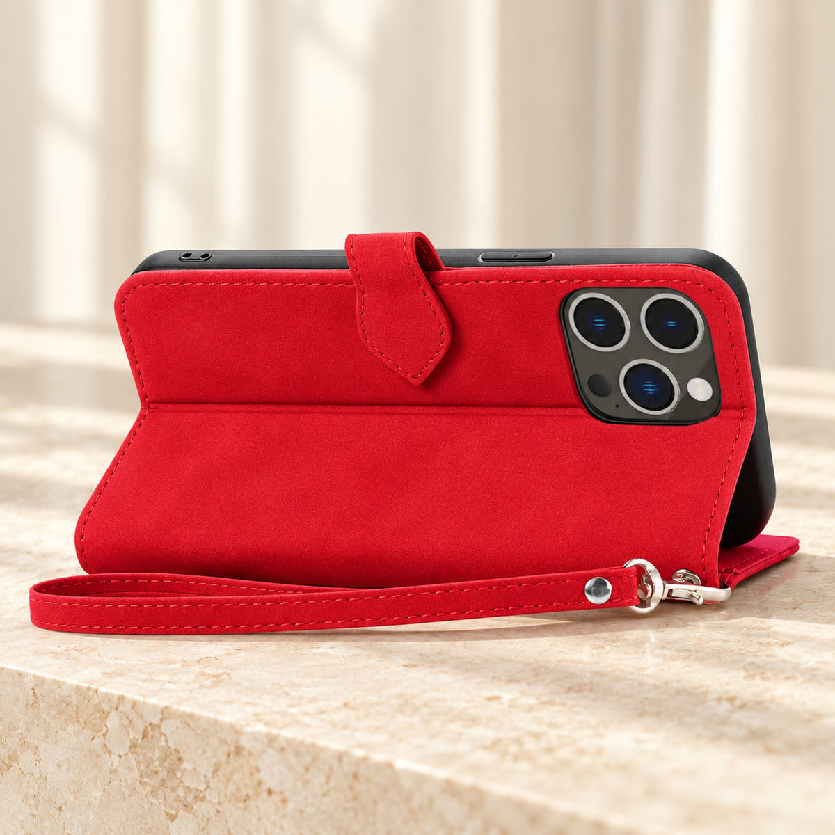 Botanical wallet iPhone case in Red folded into a landscape stand, rear view showing the plain back, camera opening and matching wrist loop.