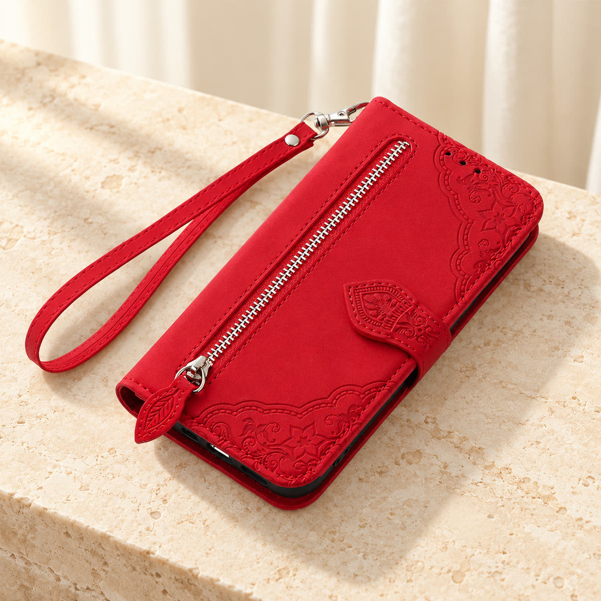 Botanical embossed wallet phone case in Red, tabletop view of the closed folio with external zip pocket and matching wrist strap.
