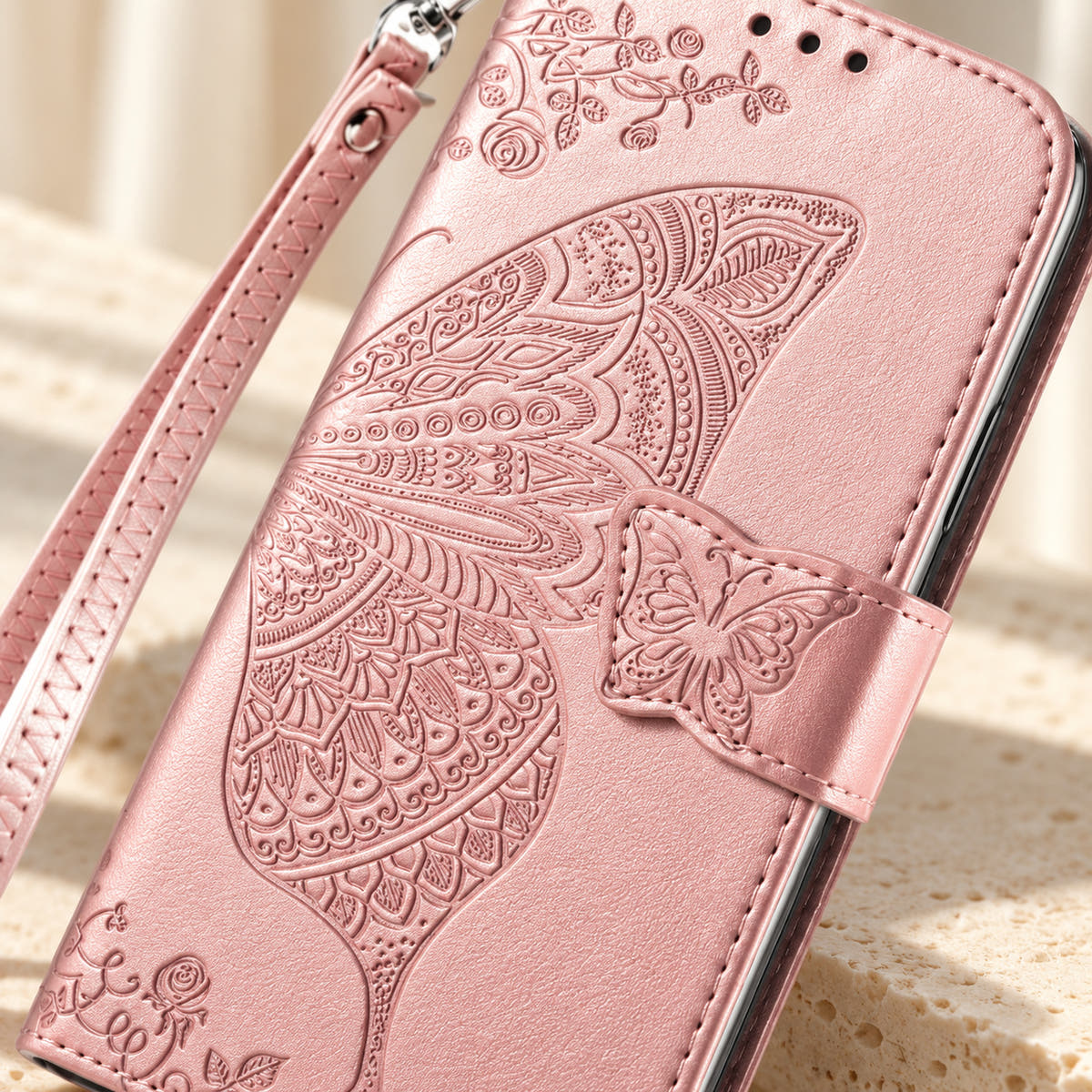 Close-up of the Baby Pink Butterfly wallet phone case showing the intricate embossed wing, small butterfly tab and stitched edge.