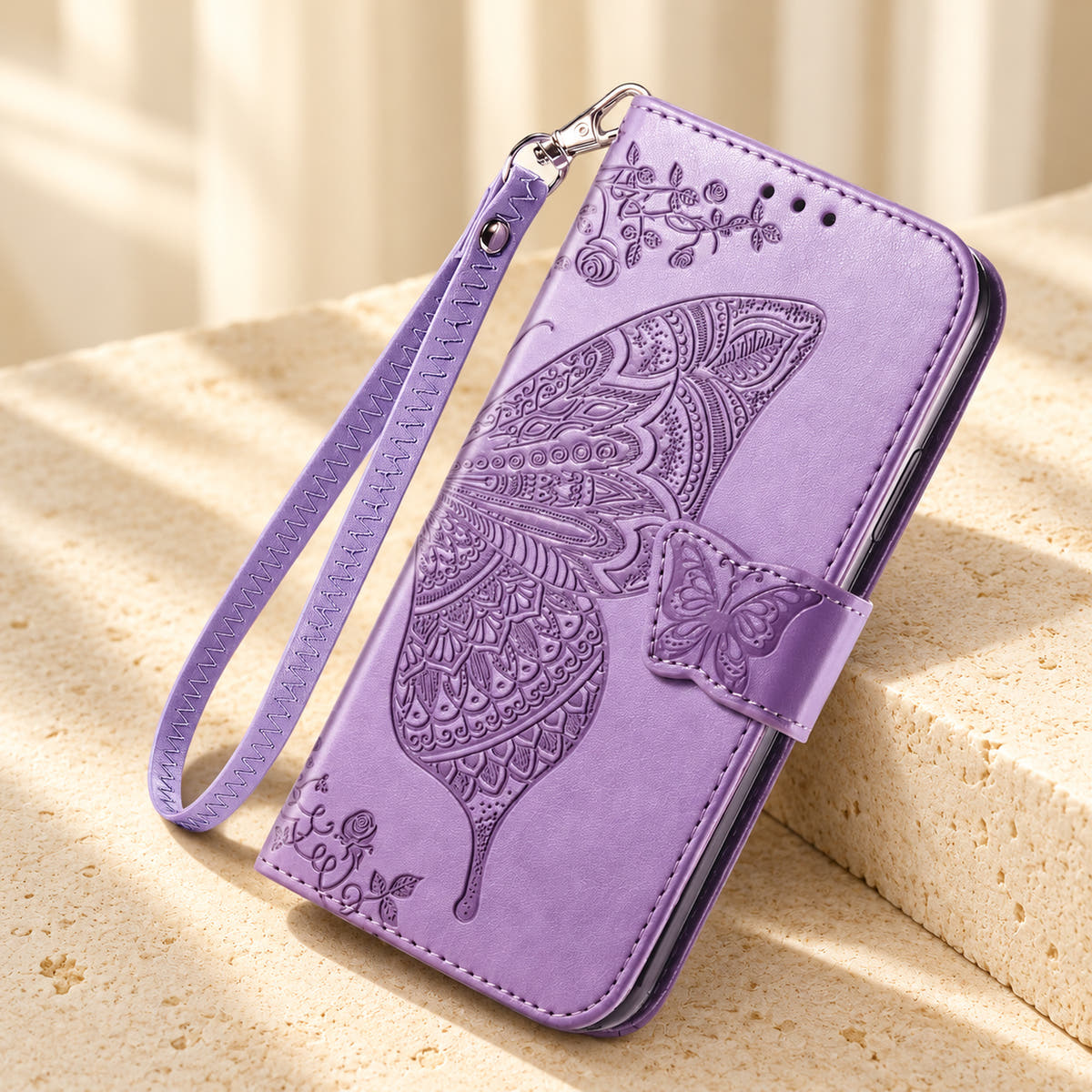 Butterfly embossed iPhone wallet case in Lavender, tabletop front view showing the detailed wing, tab closure and clip-on wrist loop.