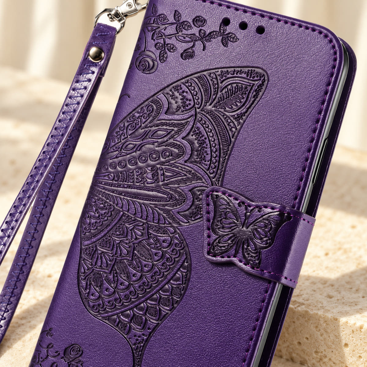 Close-up of the Purple Butterfly wallet phone case showing the intricate embossed wing, small butterfly tab and stitched edge.