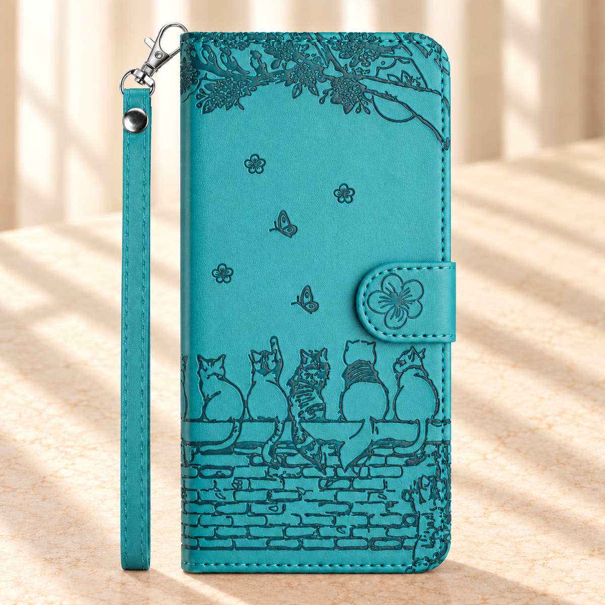Front of the Turquoise Cat Garden wallet case with embossed cats on a brick wall, flower closure and wrist strap.