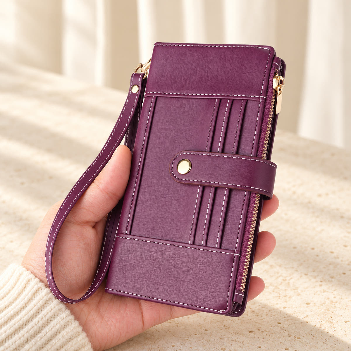 Elaris Crossbody iPhone wallet case in Purple, closed handheld view with wrist loop.