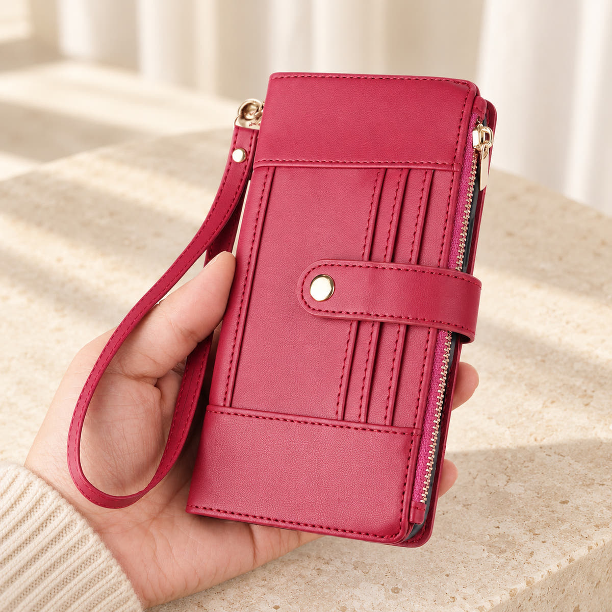 Elaris Crossbody iPhone wallet case in Red, closed handheld view with wrist loop.