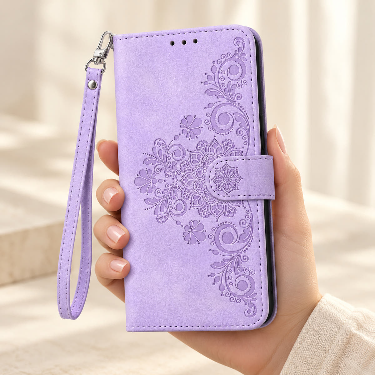 Floral embossed iPhone flip wallet case in Lavender — closed front held in hand with matching wrist strap