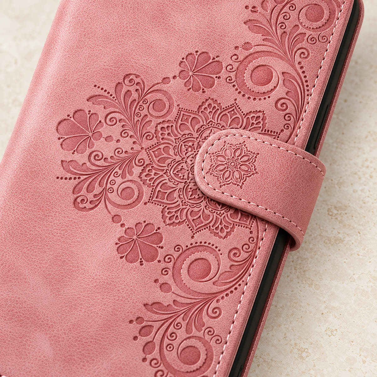 Floral embossed iPhone flip wallet case in Pink — close-up of floral embossing, closure tab and stitching