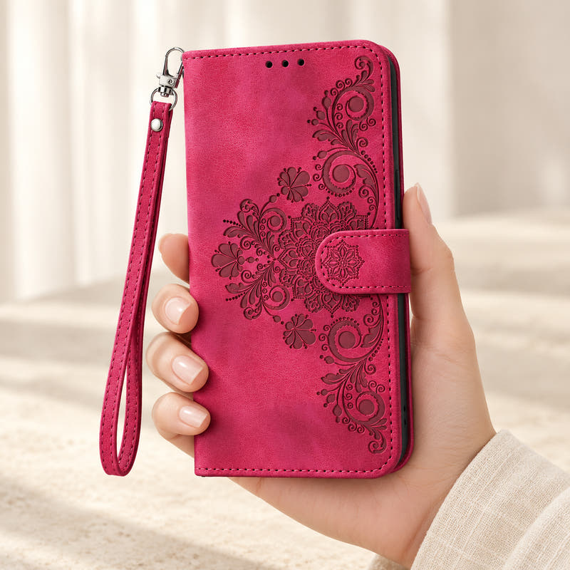 Floral embossed iPhone flip wallet case in Red — closed front held in hand with matching wrist strap