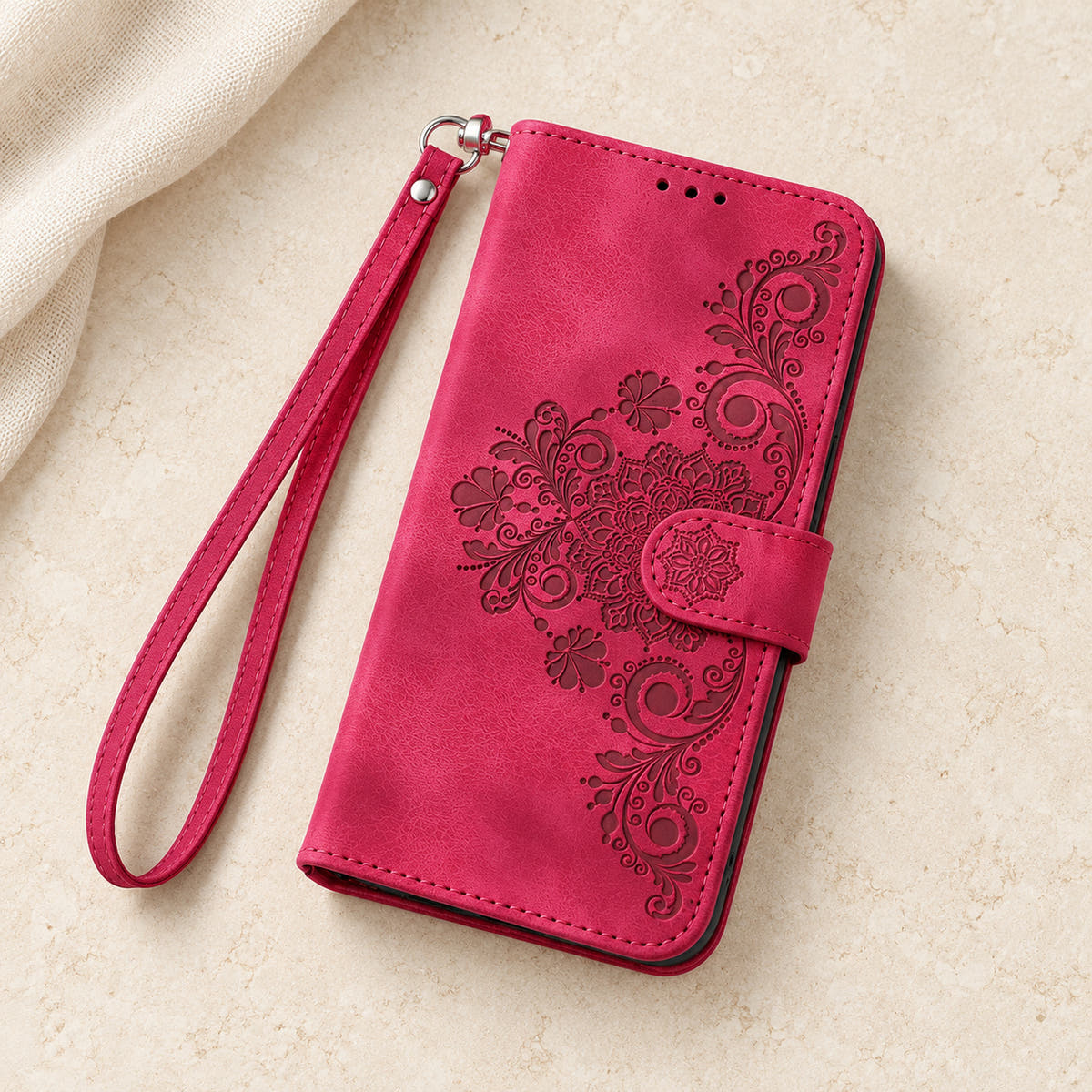 Floral embossed iPhone flip wallet case in Red — overhead view of floral front and matching wrist strap