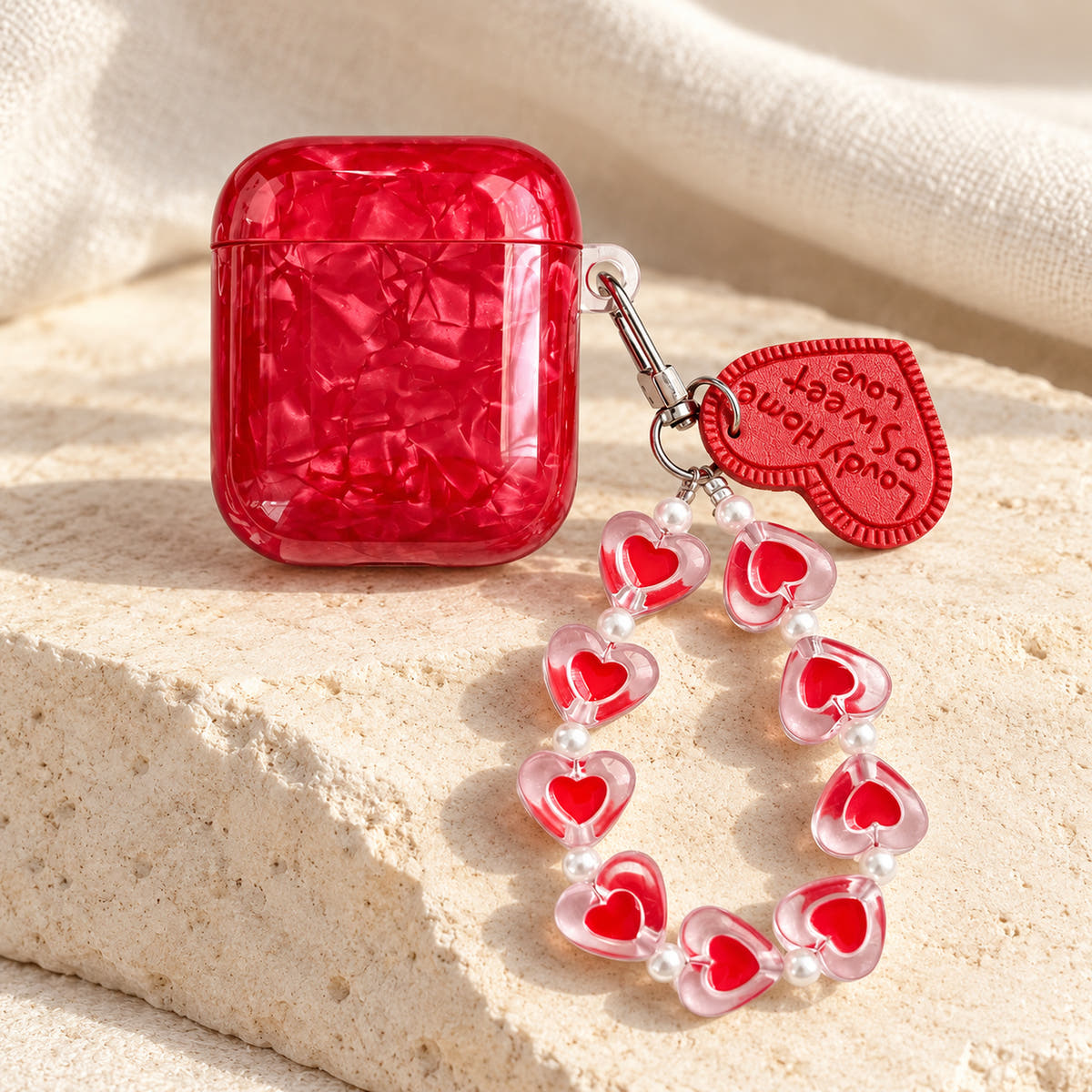 Garnet Marble AirPods case — tall tabletop with glossy red finish and heart-bead charm strap