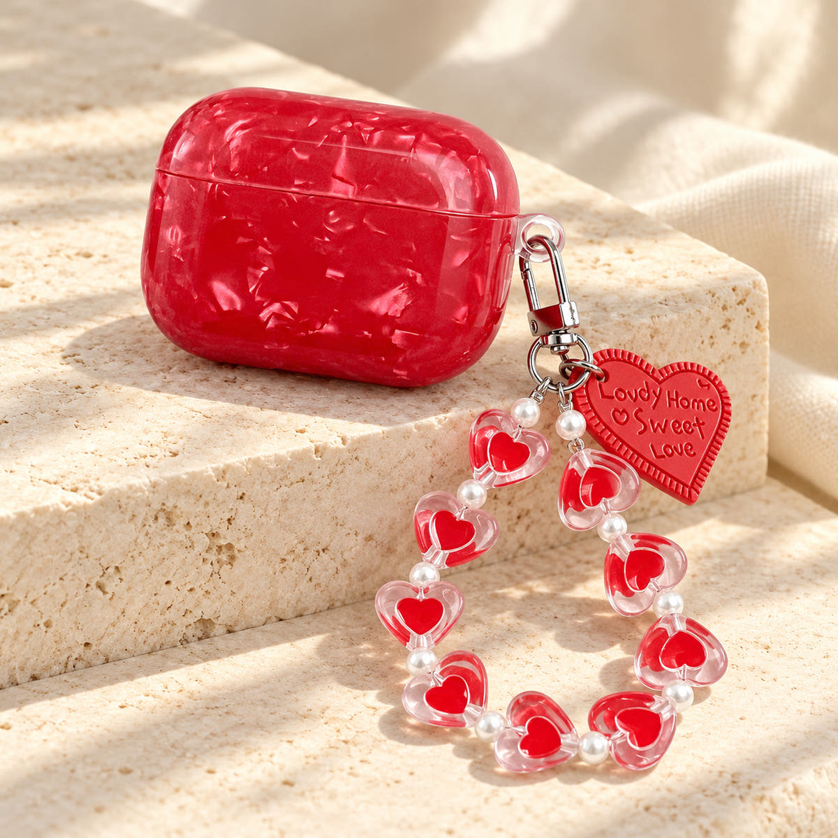 Garnet Marble AirPods case — wide angle with glossy red finish and heart-bead charm strap
