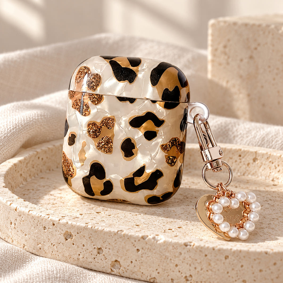 Gilded Leopard Heart AirPods case Design #2 — pedestal showing its pearl-style heart charm