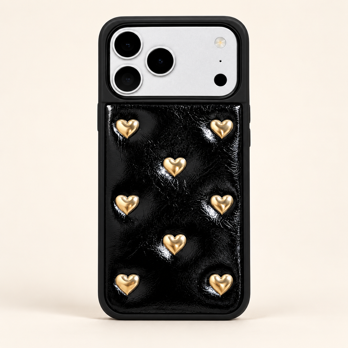 Black iPhone case with raised gold-tone hearts — full rear studio view.