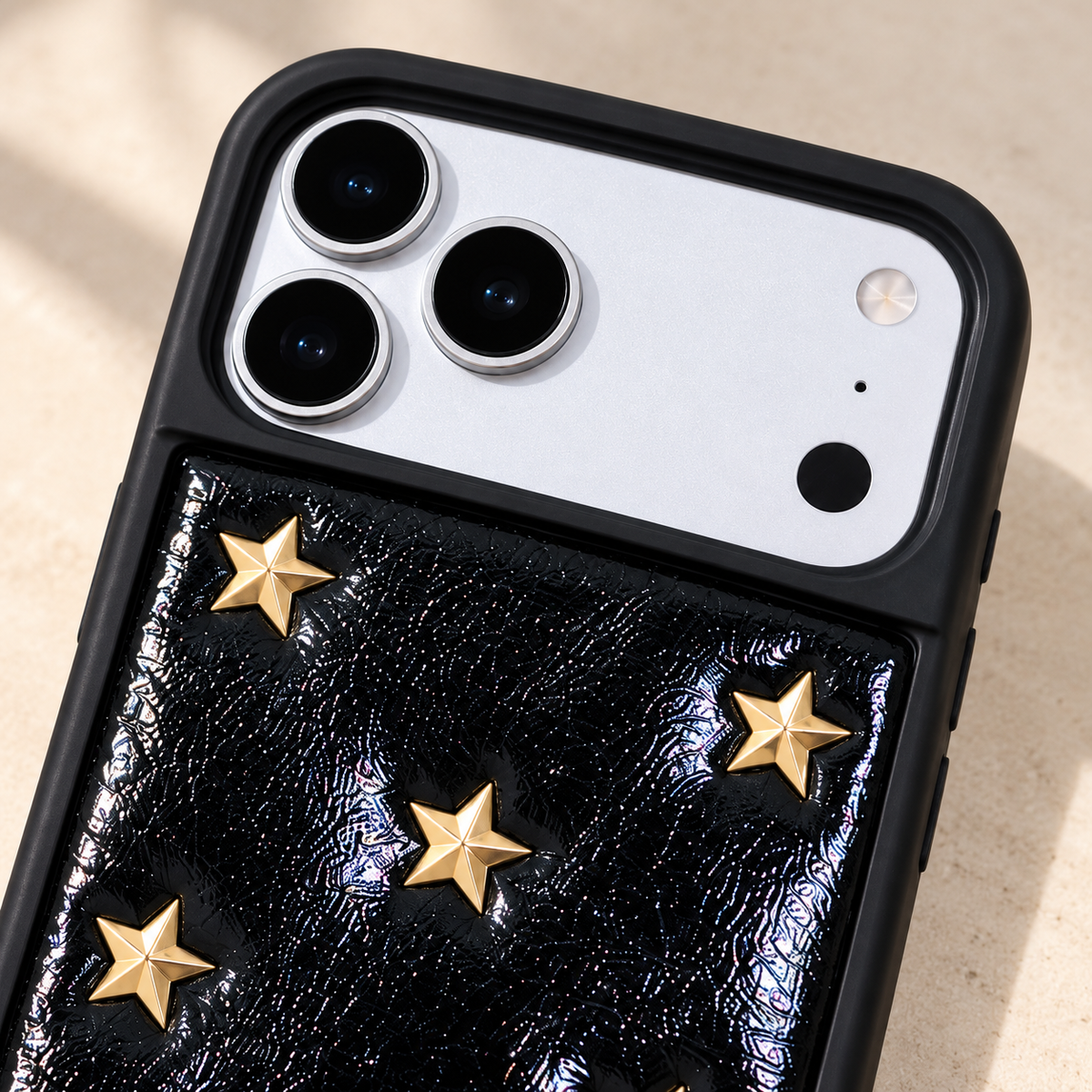 Black iPhone case with raised gold-tone stars — camera surround and upper motif view.