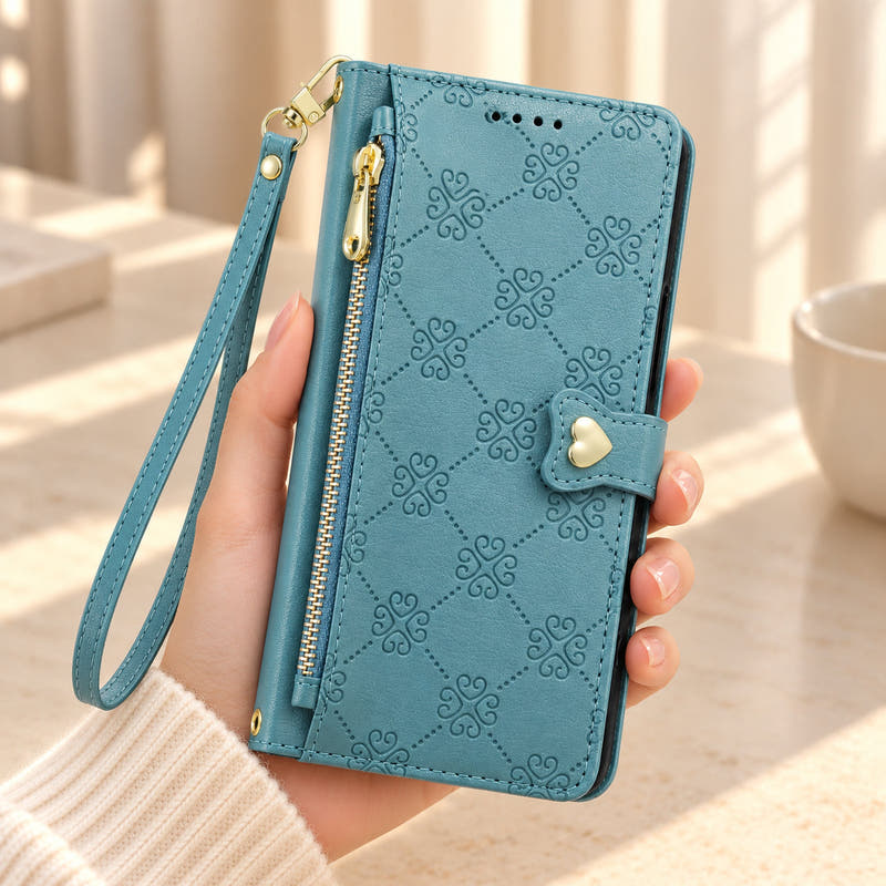 Lake Blue Heart Zip wallet phone case held in one hand, showing its embossed lattice, front zipper, gold-tone heart closure and matching wrist strap.