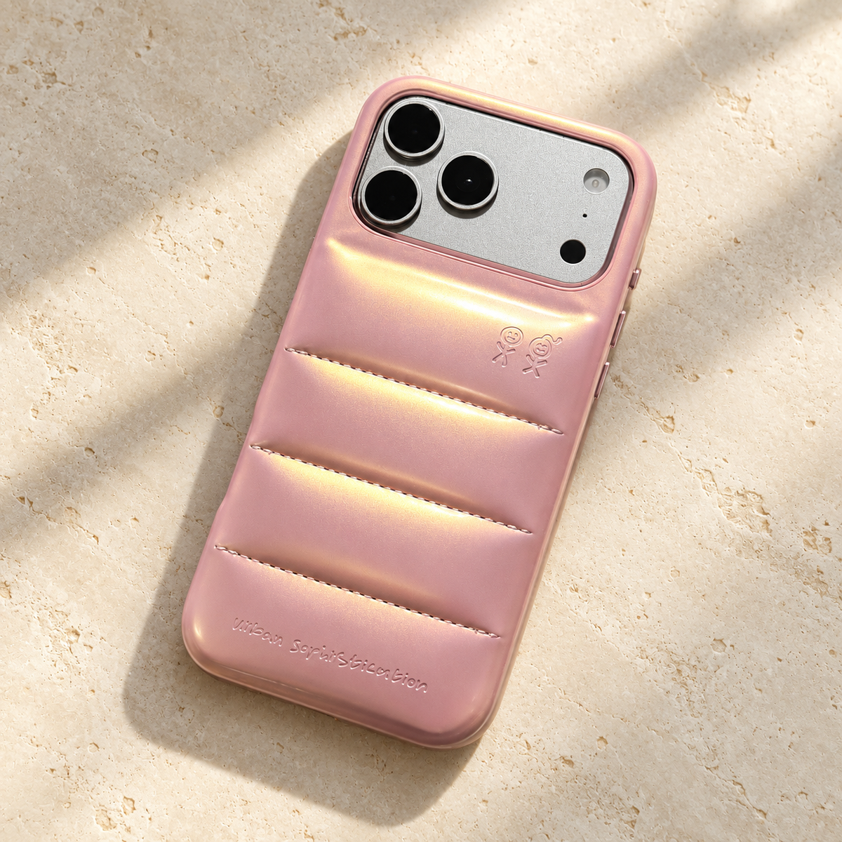 The Iridescent Pink puffer case on cream stone in gentle window light.