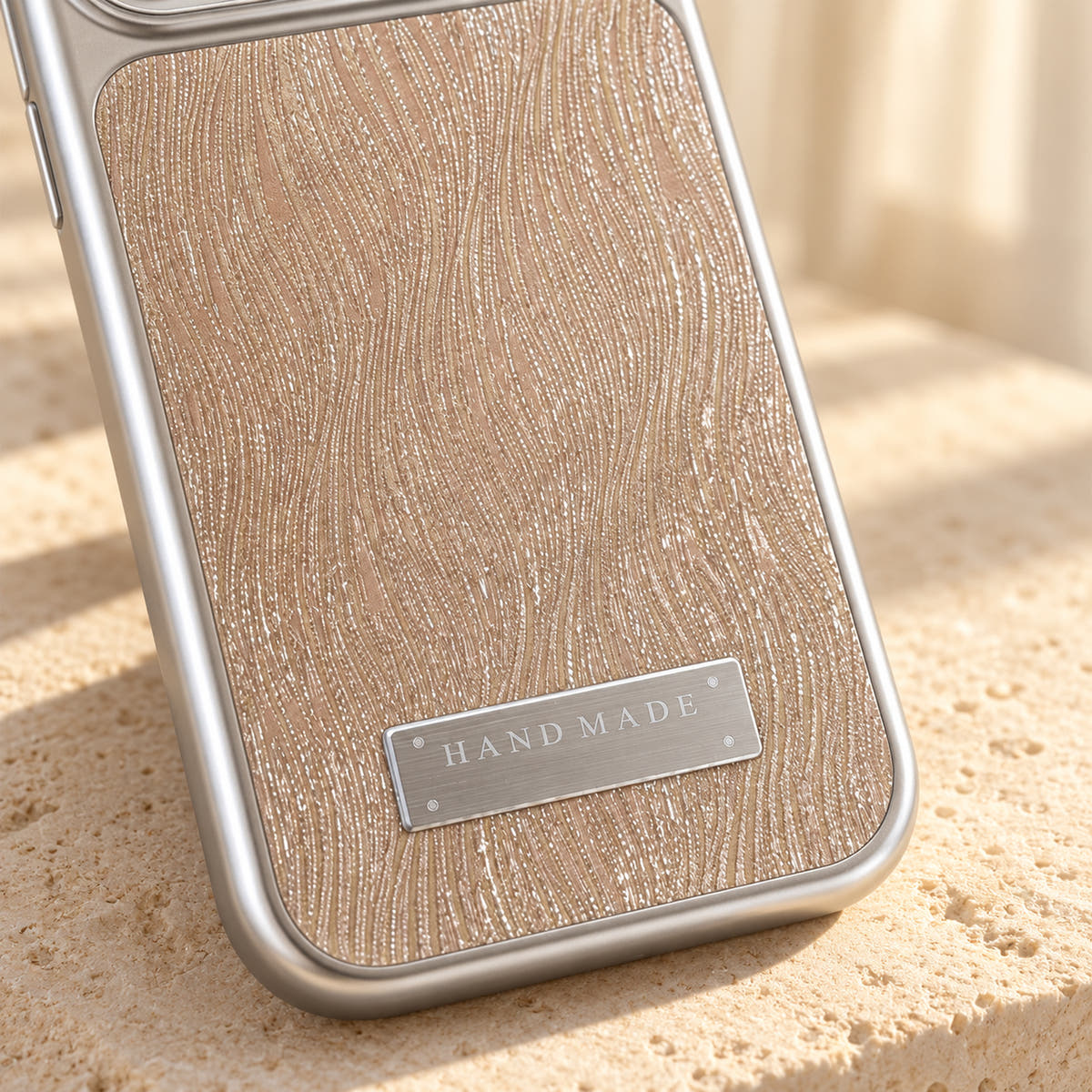 Luna Belle textured shimmer iPhone case in Beige, close-up of the wave texture and silver-tone plaque.