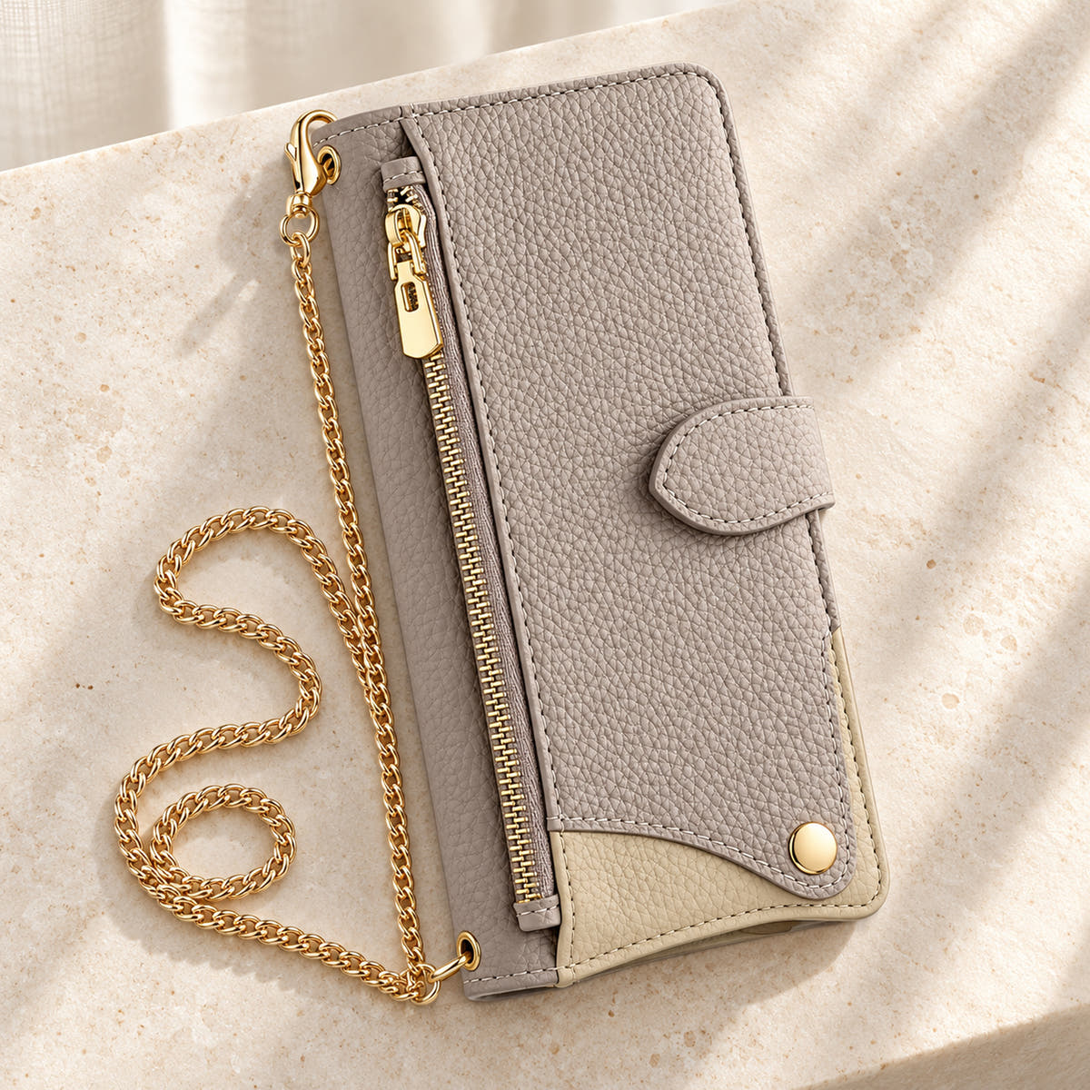 Luxe Colourblock iPhone wallet case in Beige with gold-tone chain arranged on cream limestone