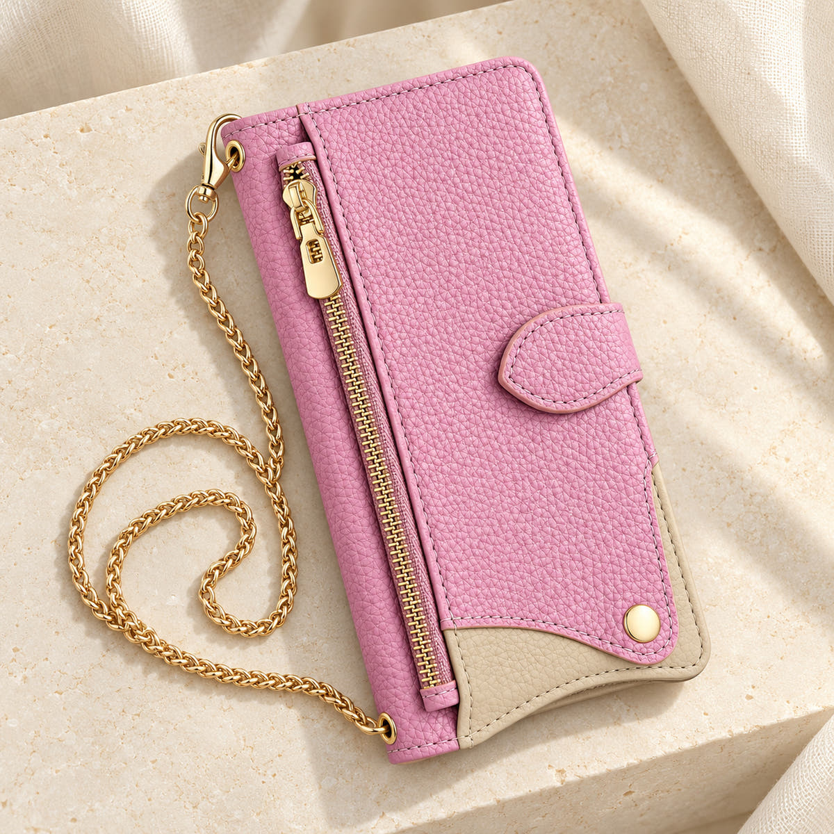 Luxe Colourblock iPhone wallet case in Pink with gold-tone chain arranged on cream limestone