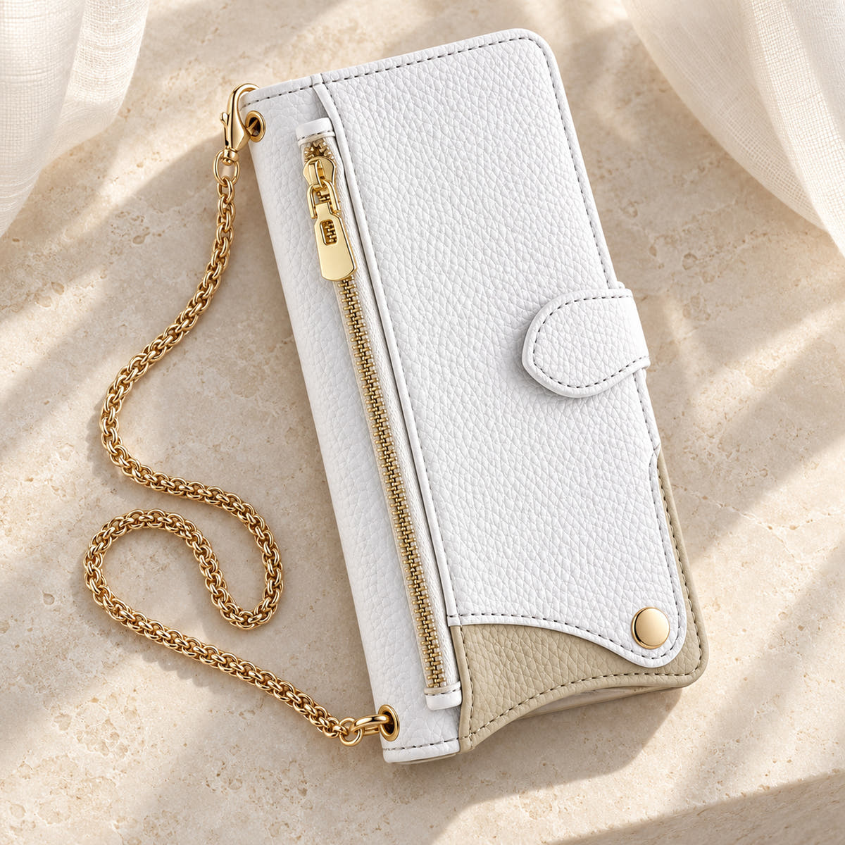 Luxe Colourblock iPhone wallet case in White with gold-tone chain arranged on cream limestone