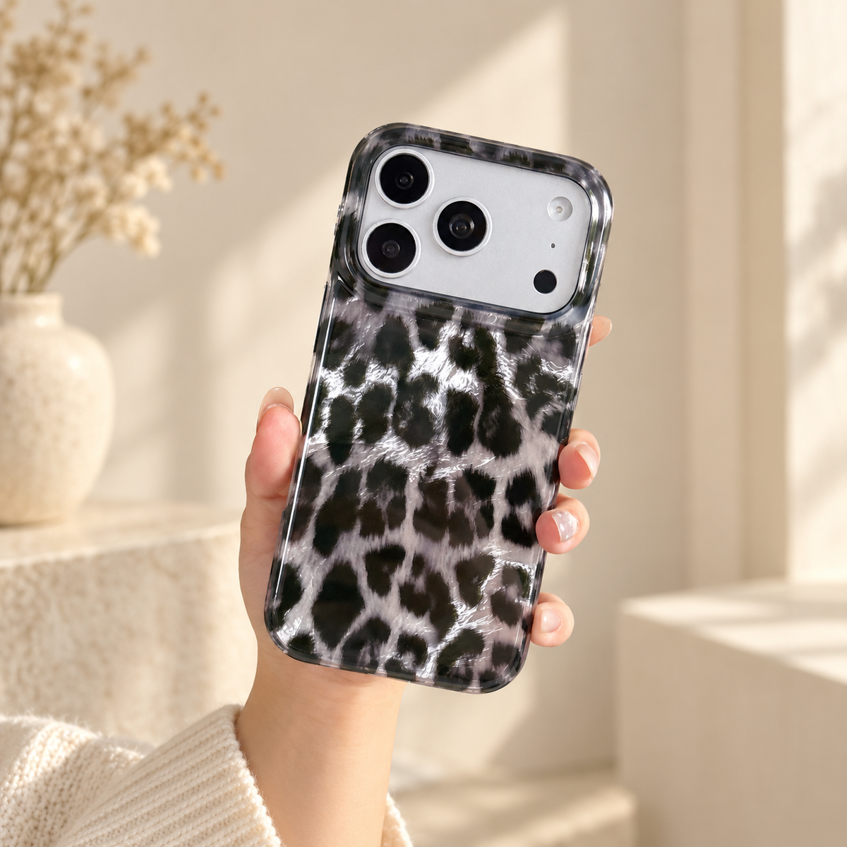 Black and silver leopard print case held in one hand in warm natural light.
