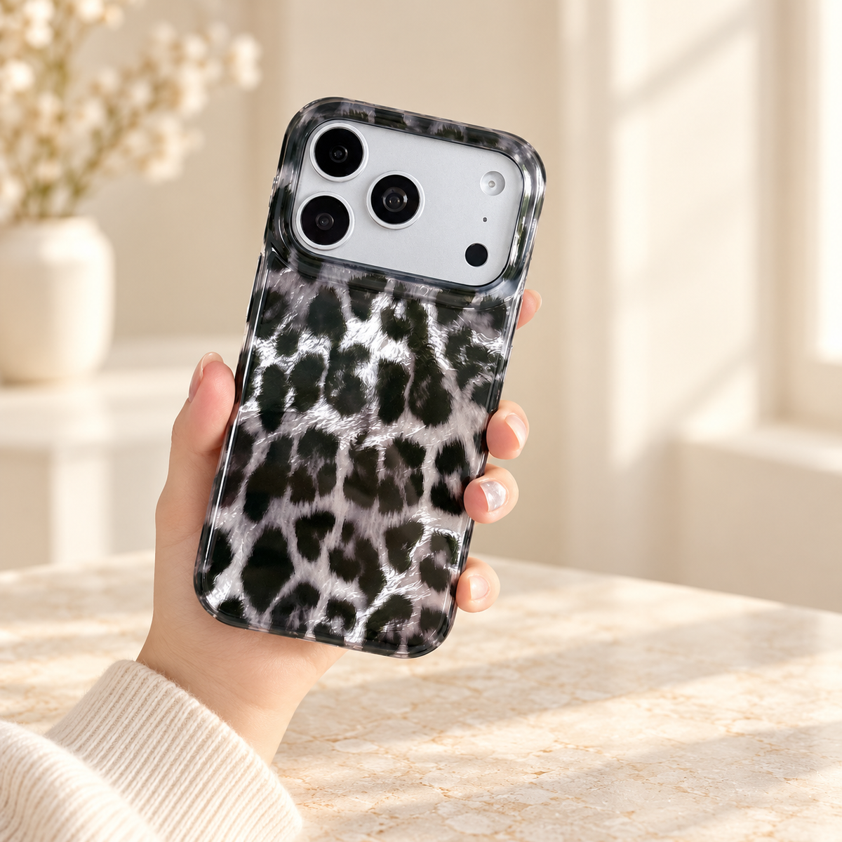 Handheld black and silver leopard print case in a softly lit cream interior.