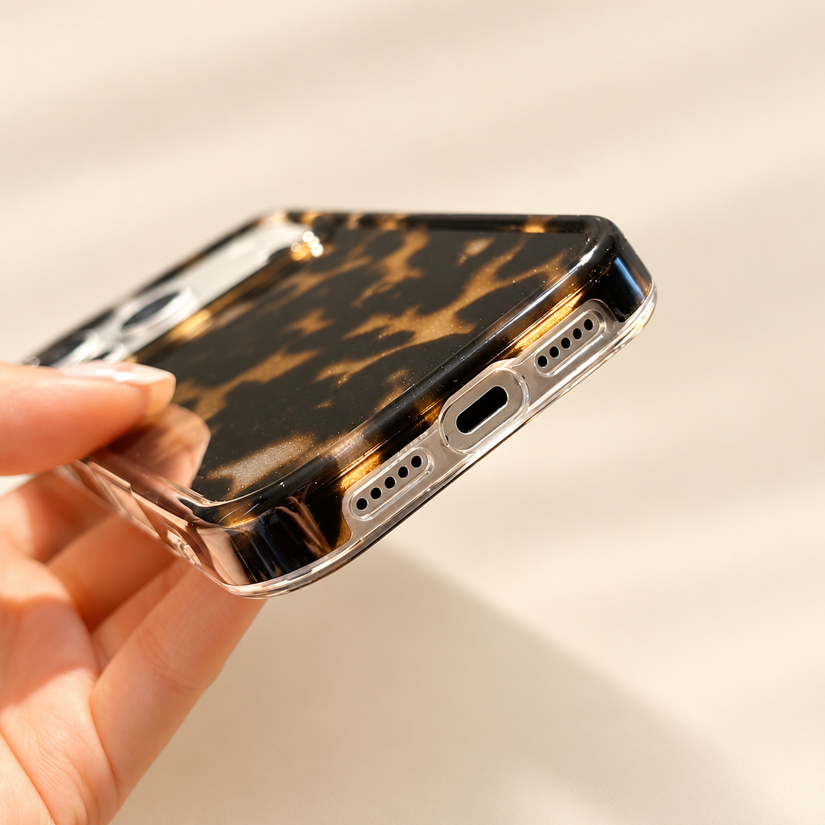 Dark Tortoiseshell iPhone case with black and warm brown mottled pattern — charging and speaker opening detail.