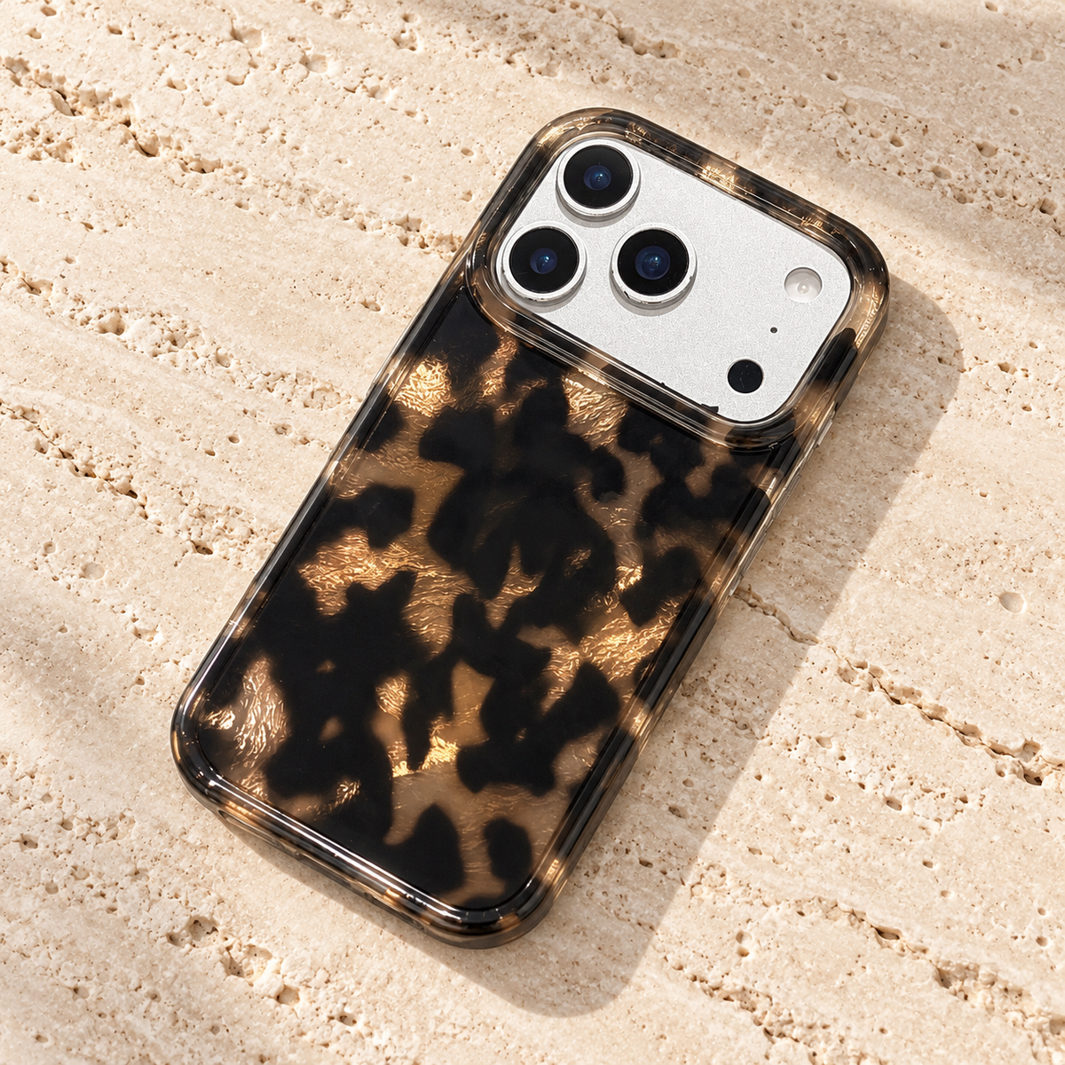 Dark Tortoiseshell iPhone case with black and warm brown mottled pattern — angled tabletop view.