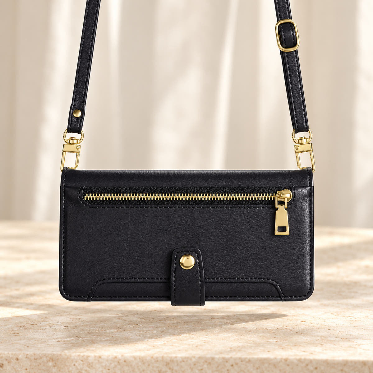 Minimal crossbody iPhone wallet case in Black — landscape view with long matching shoulder strap and gold-tone clips
