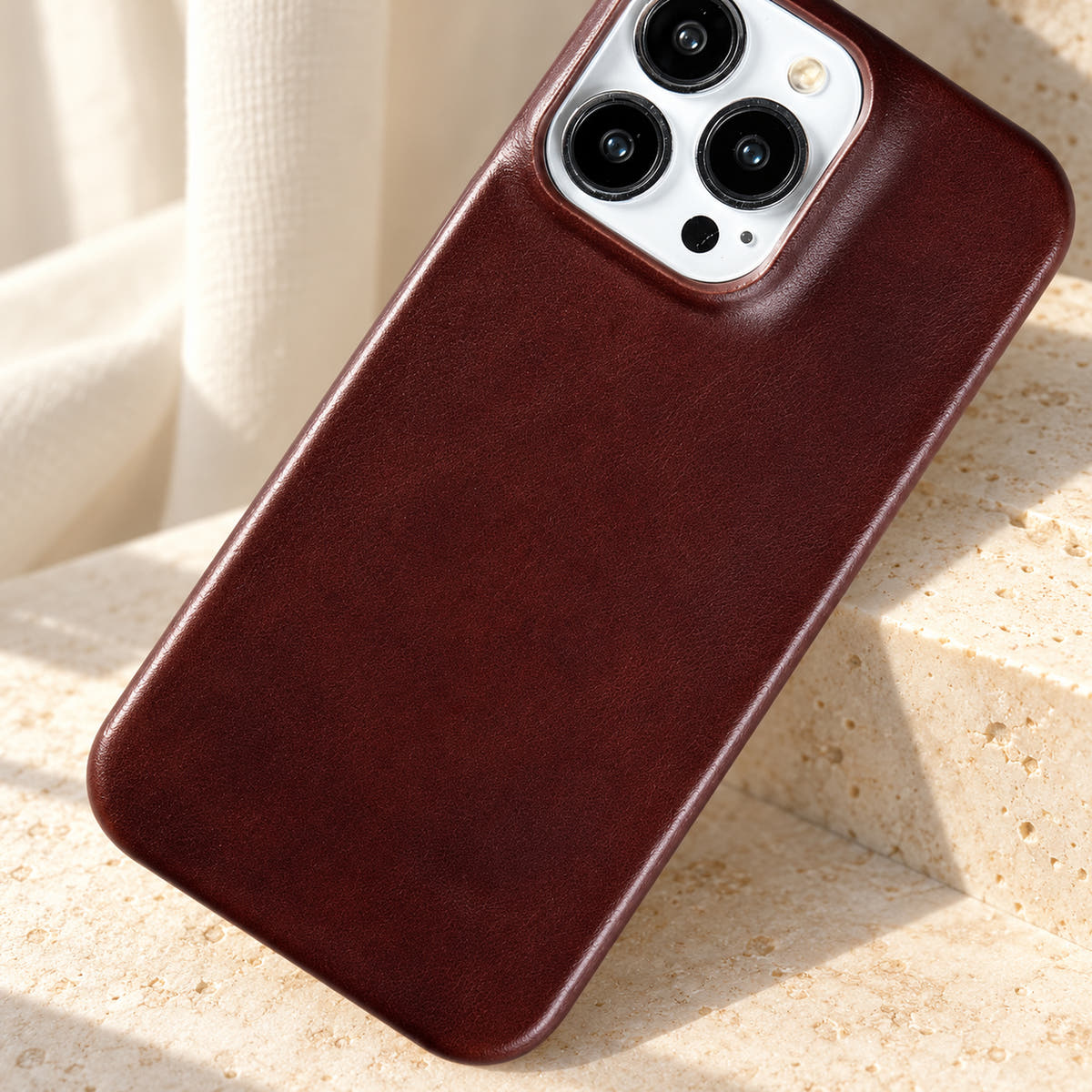 Minimal leather-look iPhone case in Burgundy, close-up of the fine-grained back and rounded corners.