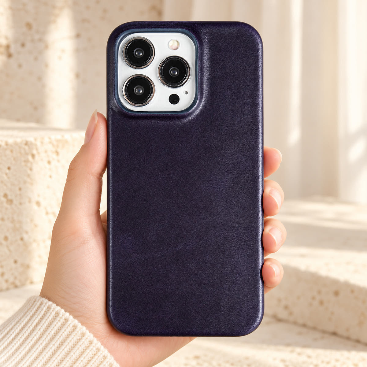 Minimal leather-look iPhone case in Dark Blue, held upright against a cream background.