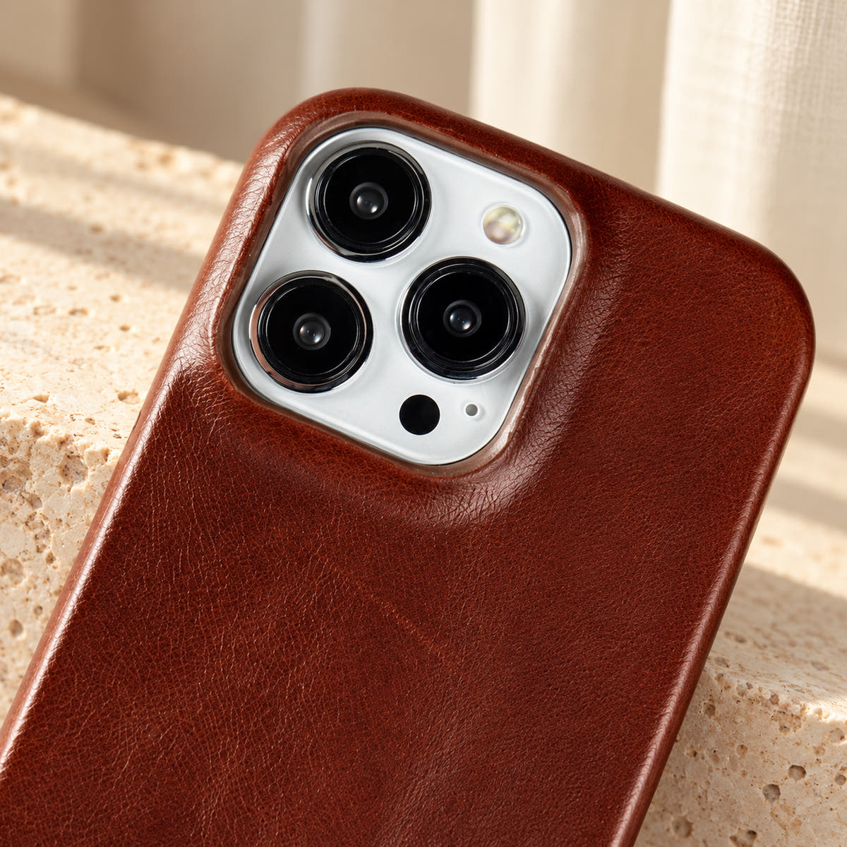 Minimal leather-look iPhone case in Dark Brown, close-up of the matching camera border.