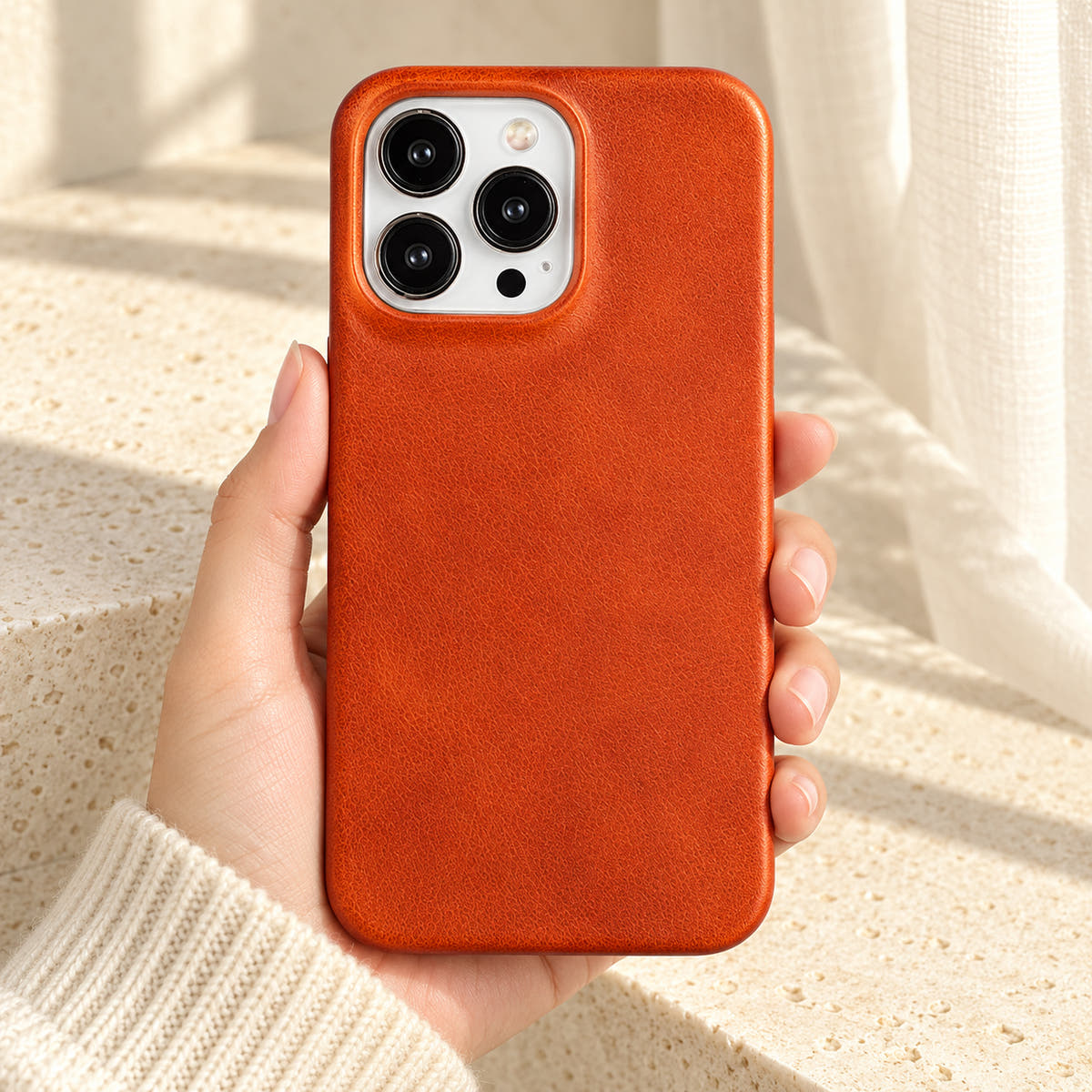 Minimal leather-look iPhone case in Light Brown, held upright against a cream background.