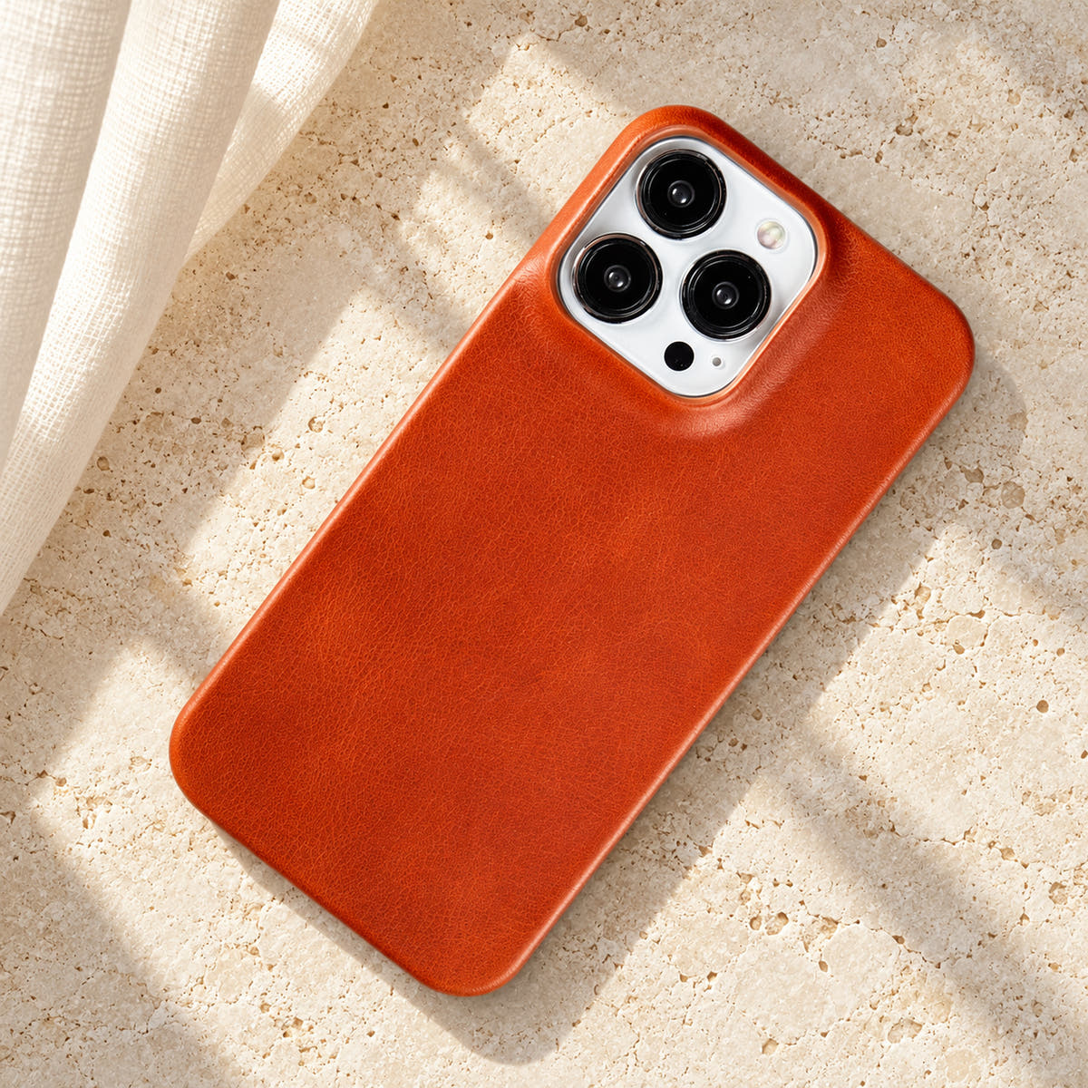 Minimal leather-look iPhone case in Light Brown, full rear view on an ivory tabletop.