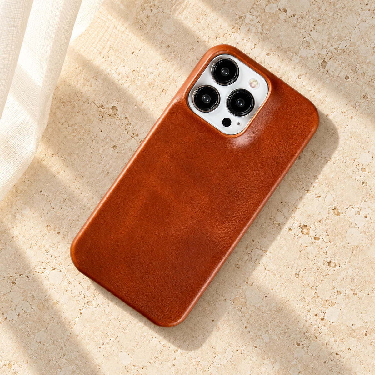 Minimal leather-look iPhone case in Orange Red, full rear view on an ivory tabletop.