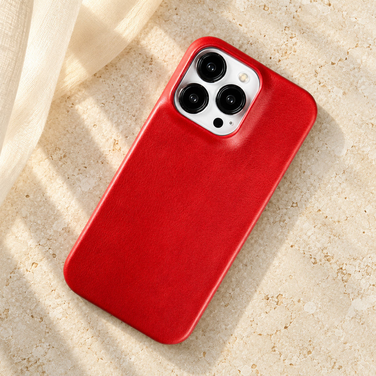 Minimal leather-look iPhone case in Red, full rear view on an ivory tabletop.