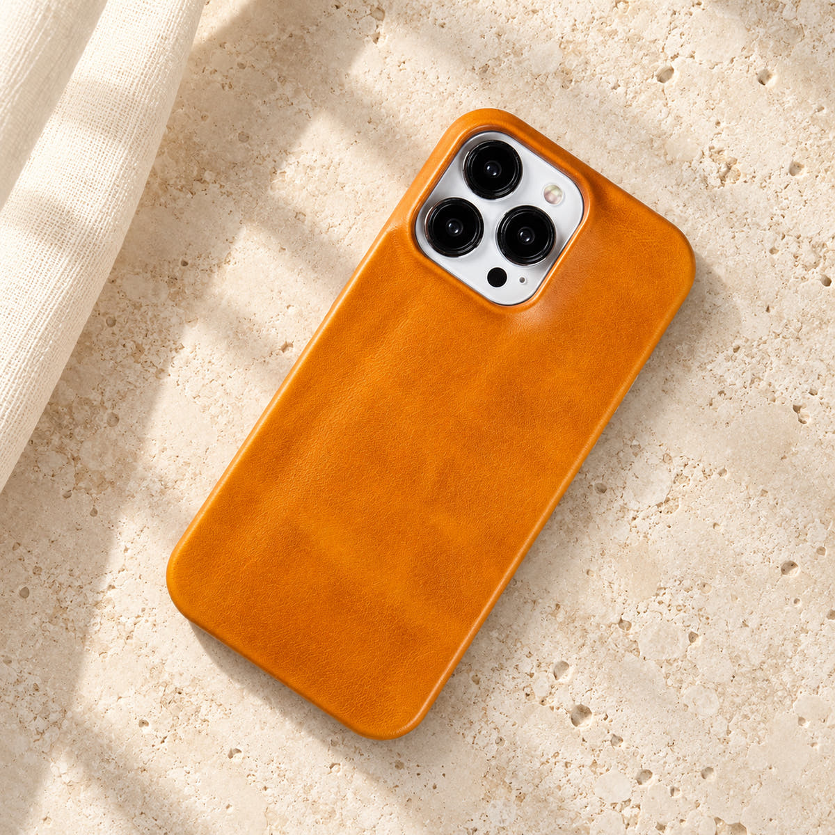 Minimal leather-look iPhone case in Yellow, full rear view on an ivory tabletop.