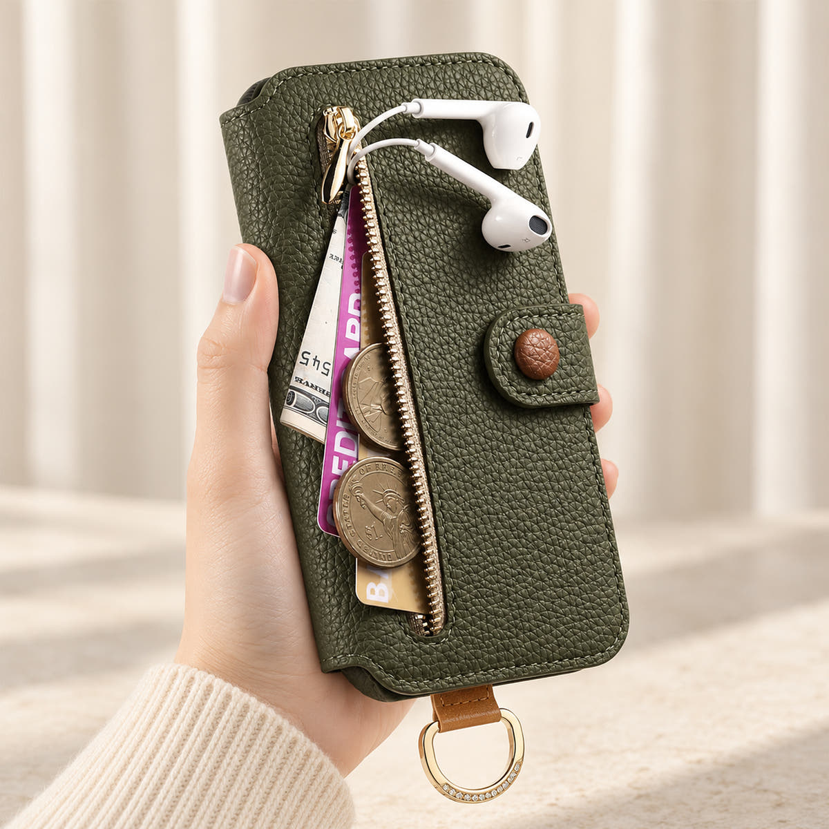 Forest Green iPhone wallet case with the front zip pocket open, showing illustrated cards, notes, coins and wired earphones beside the buttoned closure