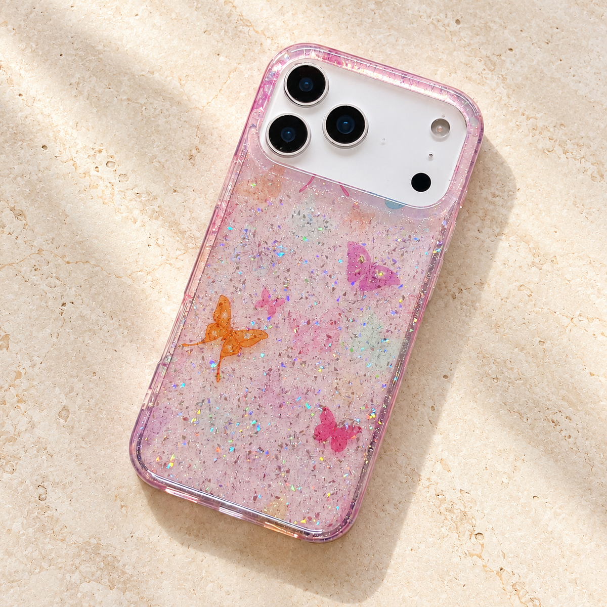 Butterfly Pink case lying diagonally on cream limestone with its pastel butterfly print visible.
