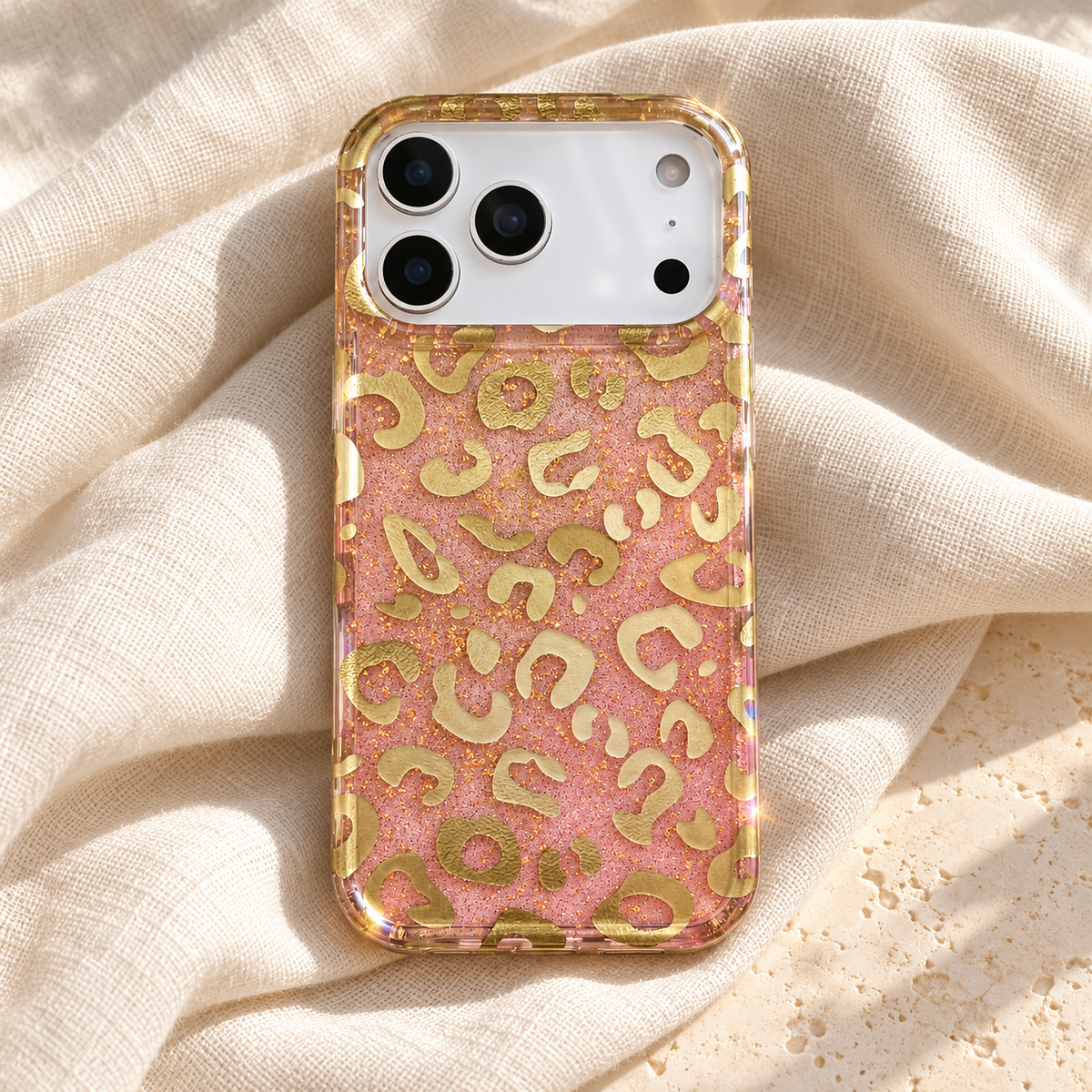 Golden Blush Leopard case resting on ivory linen with its full pink-and-gold design visible.