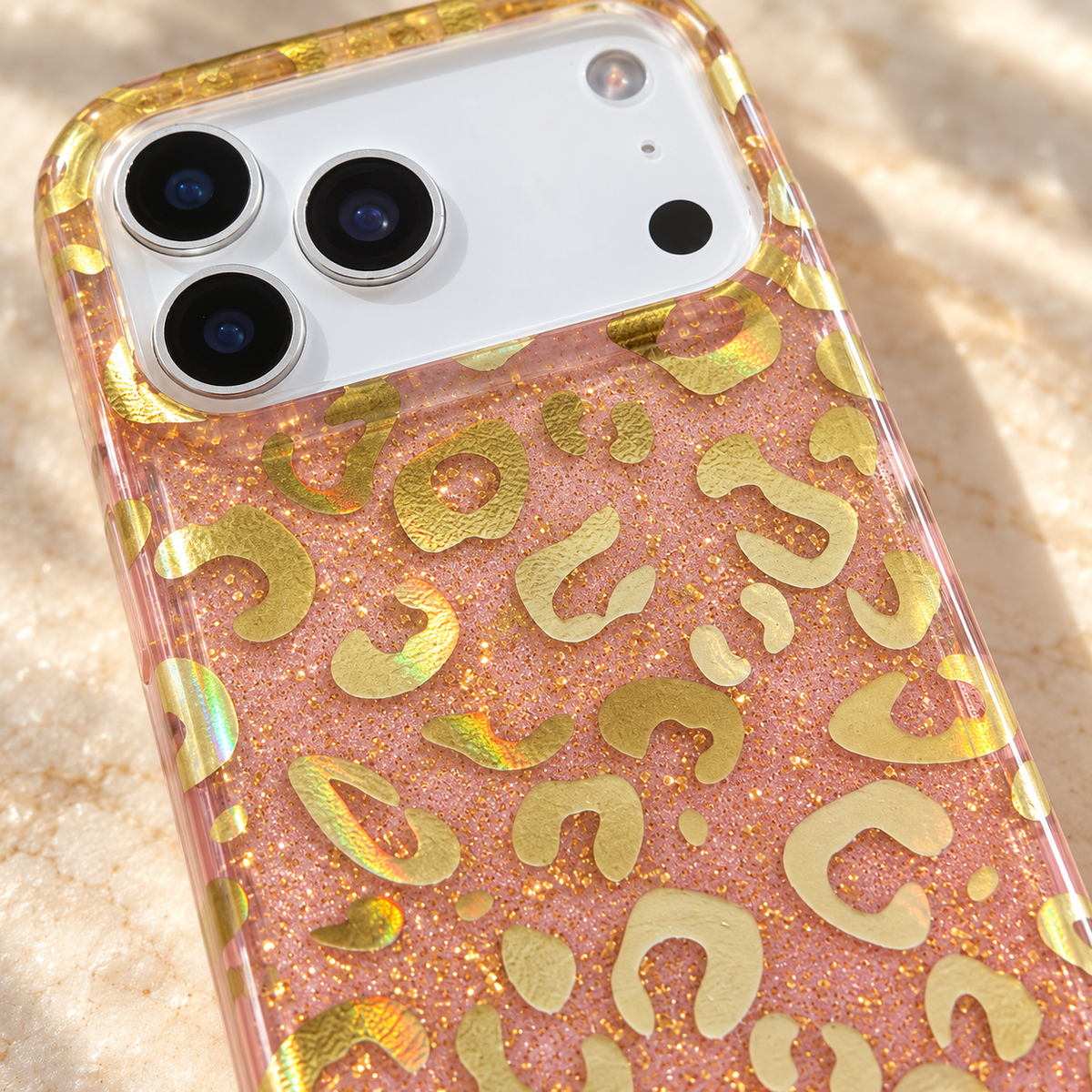 Macro detail of the Golden Blush Leopard case's reflective gold-tone motifs and fine pink sparkle.