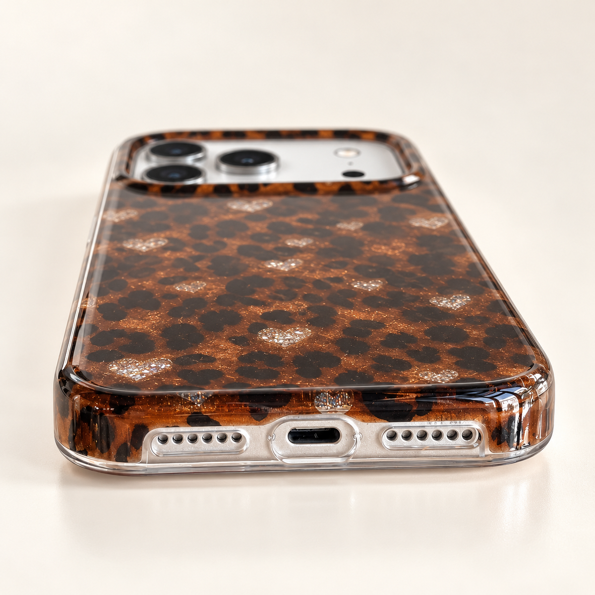 Low-angle view of the Amber Leopard Heart case’s central charging opening and lower-edge perforations.