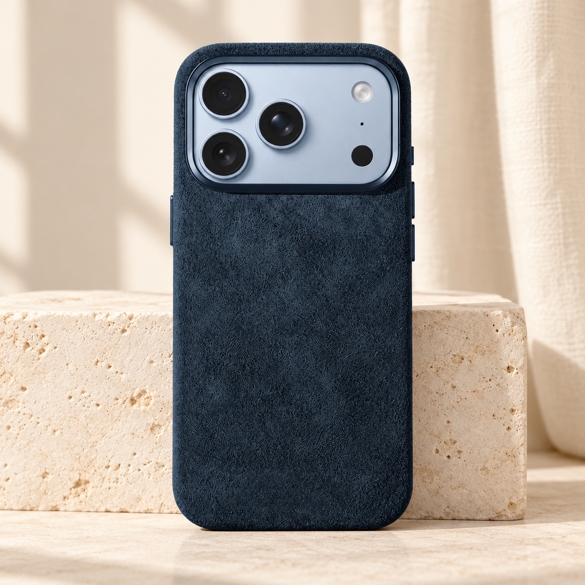 Deep Navy suede-look textured iPhone case shown upright beside a pale stone block.